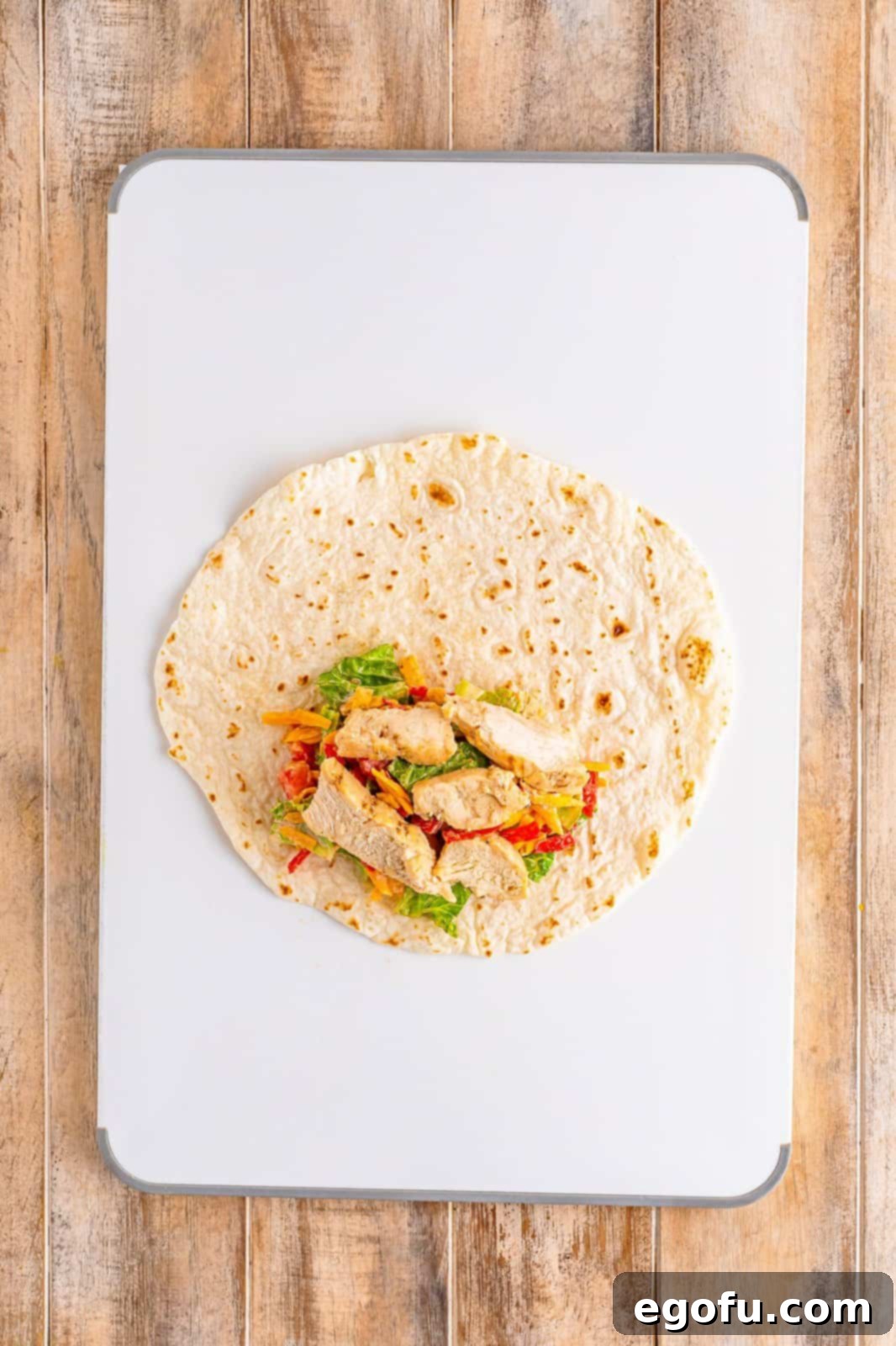 A burrito-sized tortilla layered with the fresh Southwest Chicken filling, ready to be rolled.