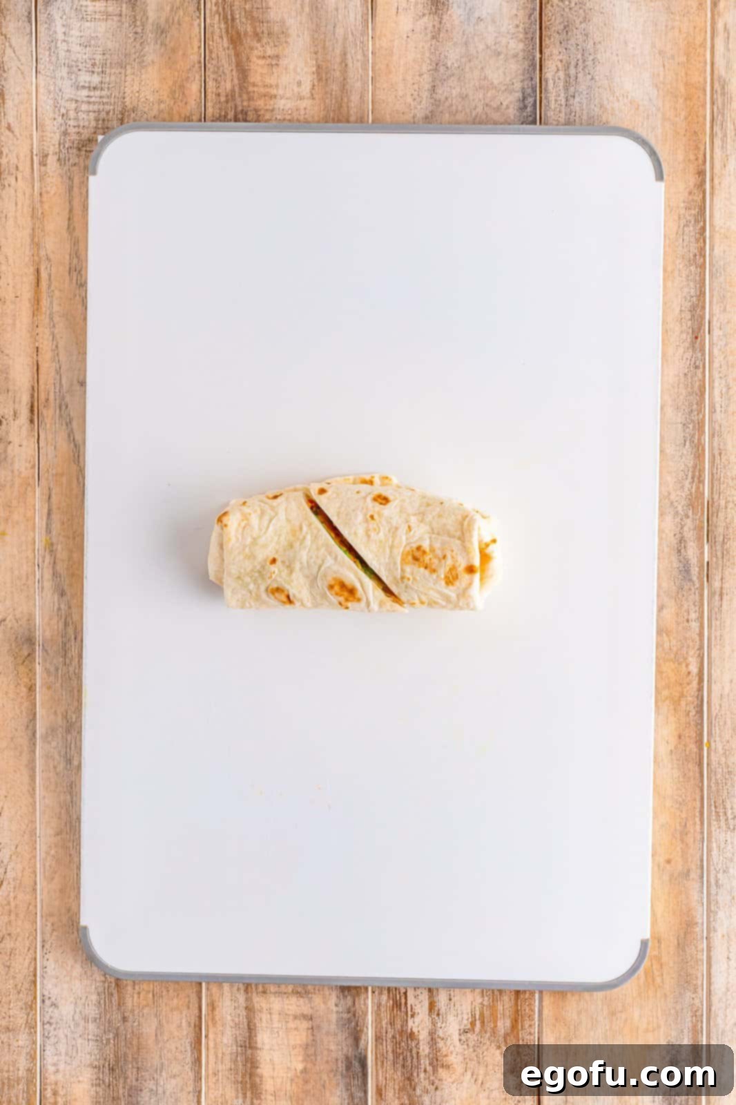 A freshly cut Southwest Chicken Wrap resting on a wooden cutting board, revealing its colorful interior.