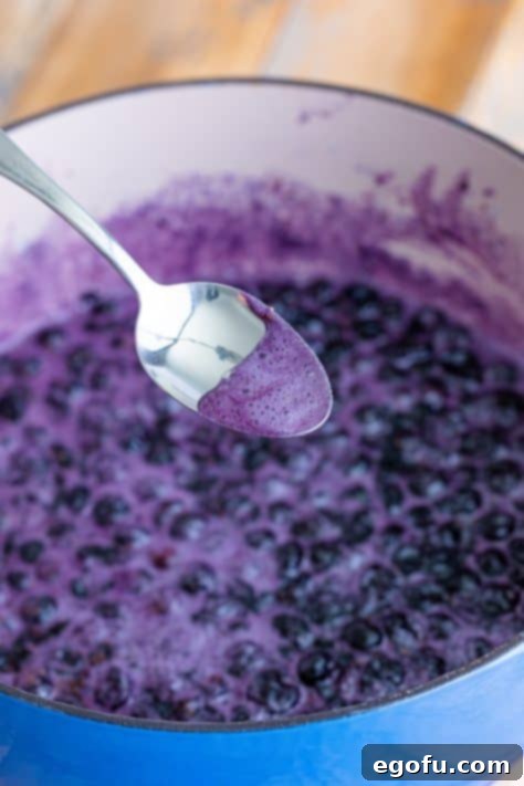 A spoon holding some foam from the jam.