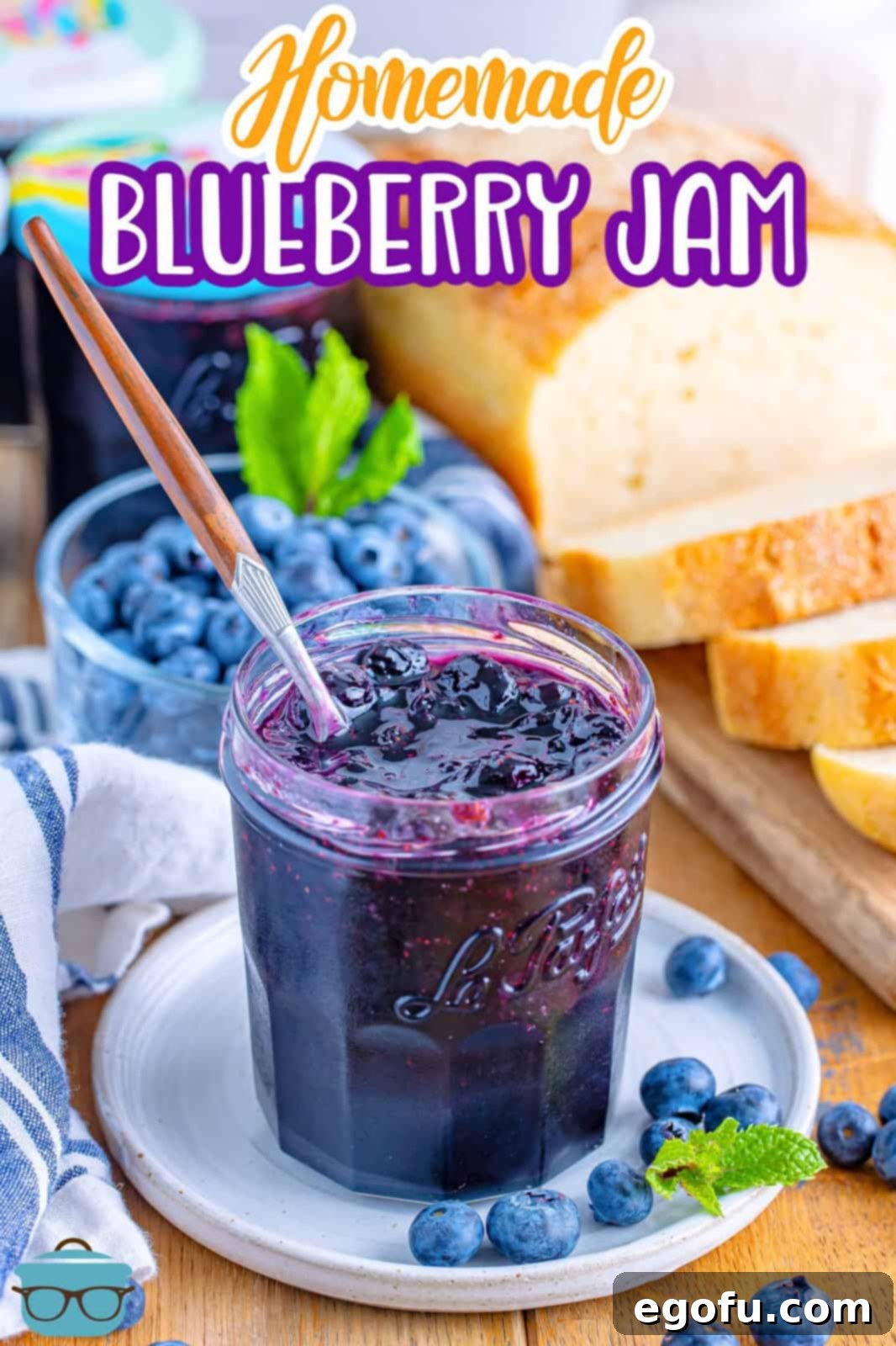 A jar of homemade blueberry jam with a spoon in it.