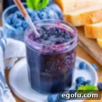 A small plate with a jar of homemade blueberry jam.