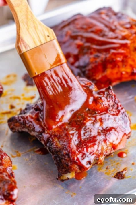 brushing BBQ sauce on the cooked ribs.