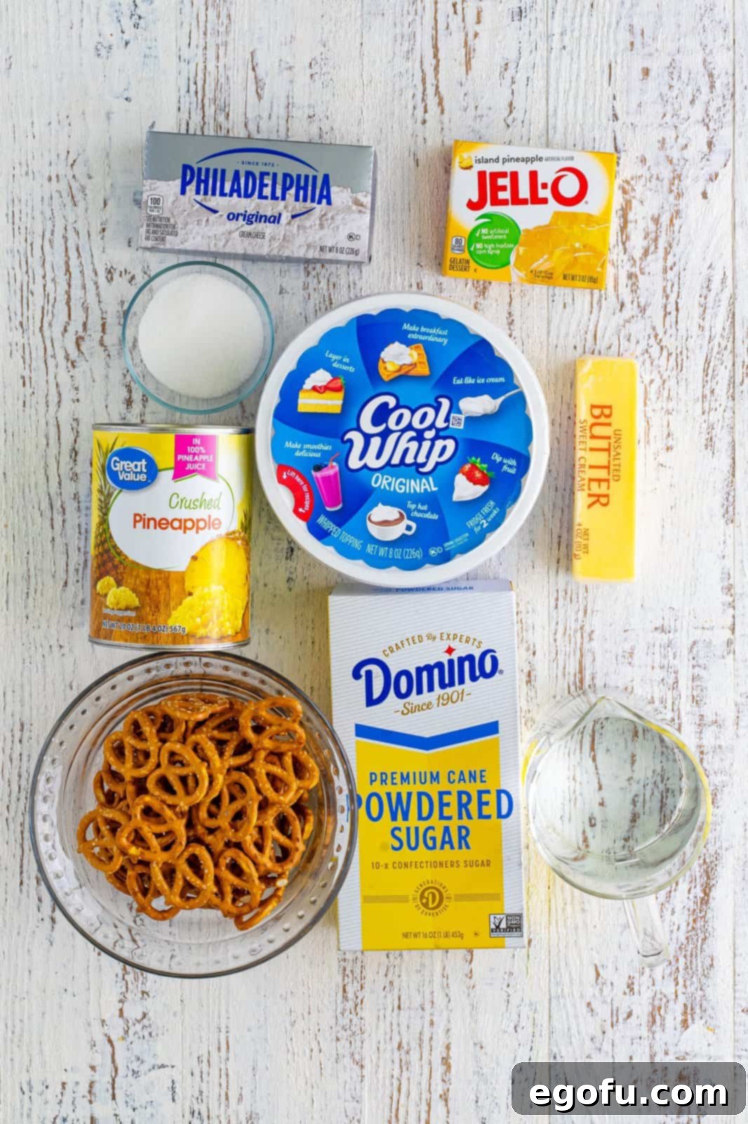 Cool Whip, pineapple chunks, pretzels, butter, sugar, cream cheese, powdered sugar, Pineapple Jello and water. 