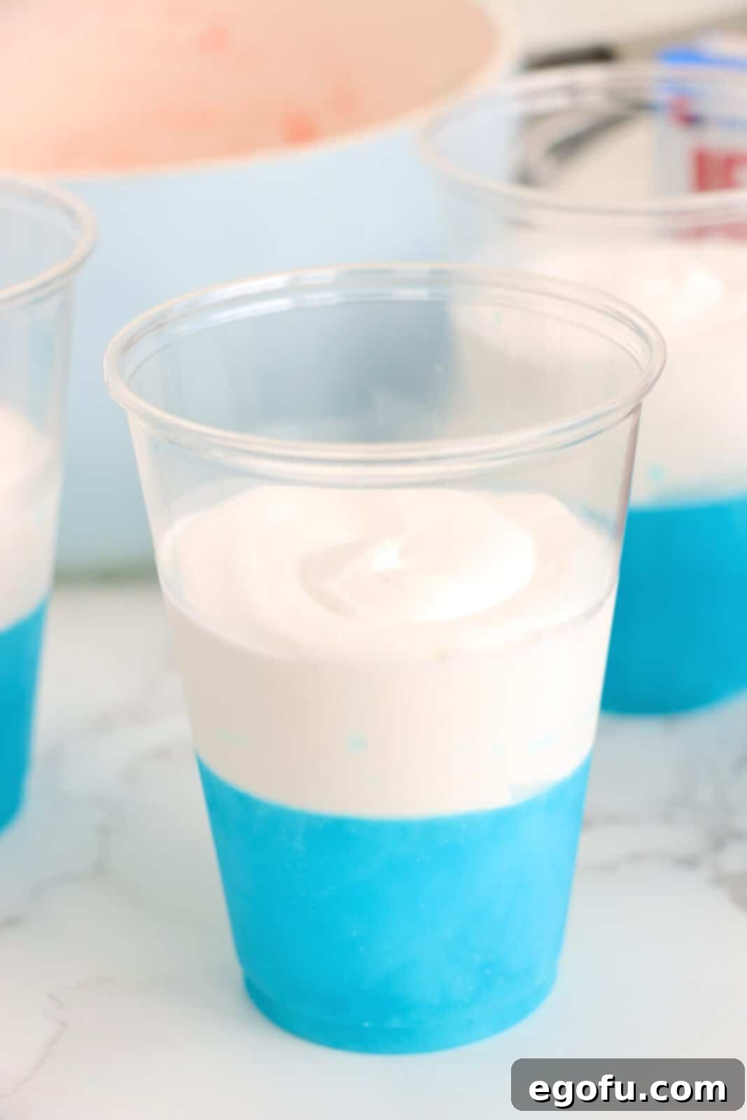 Festive Tri-Color Jell-O Cups 5 Berry Blue Jello layer topped with a white whipped cream layer in a clear cup.