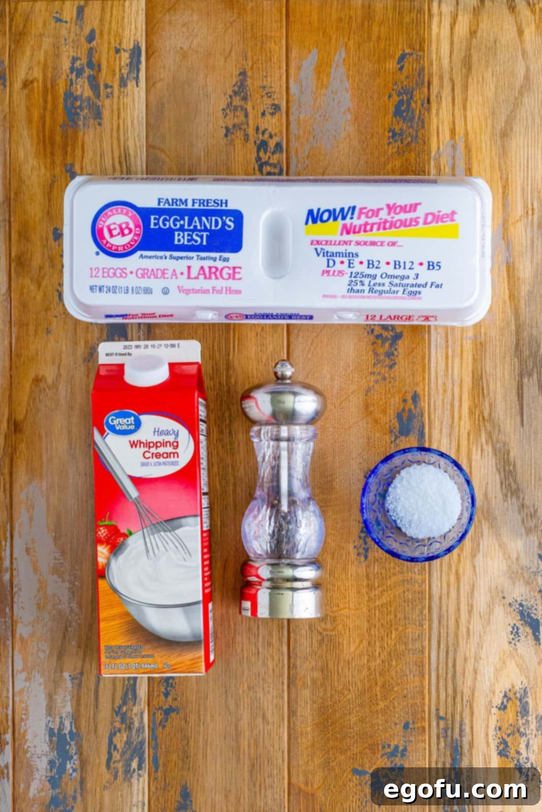 A minimalist flat lay of eggs, a small bowl of heavy cream, a pinch of salt, and freshly ground black pepper – the core ingredients for baked eggs.