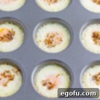A muffin tin with perfectly baked eggs in each cup, golden and ready to serve.