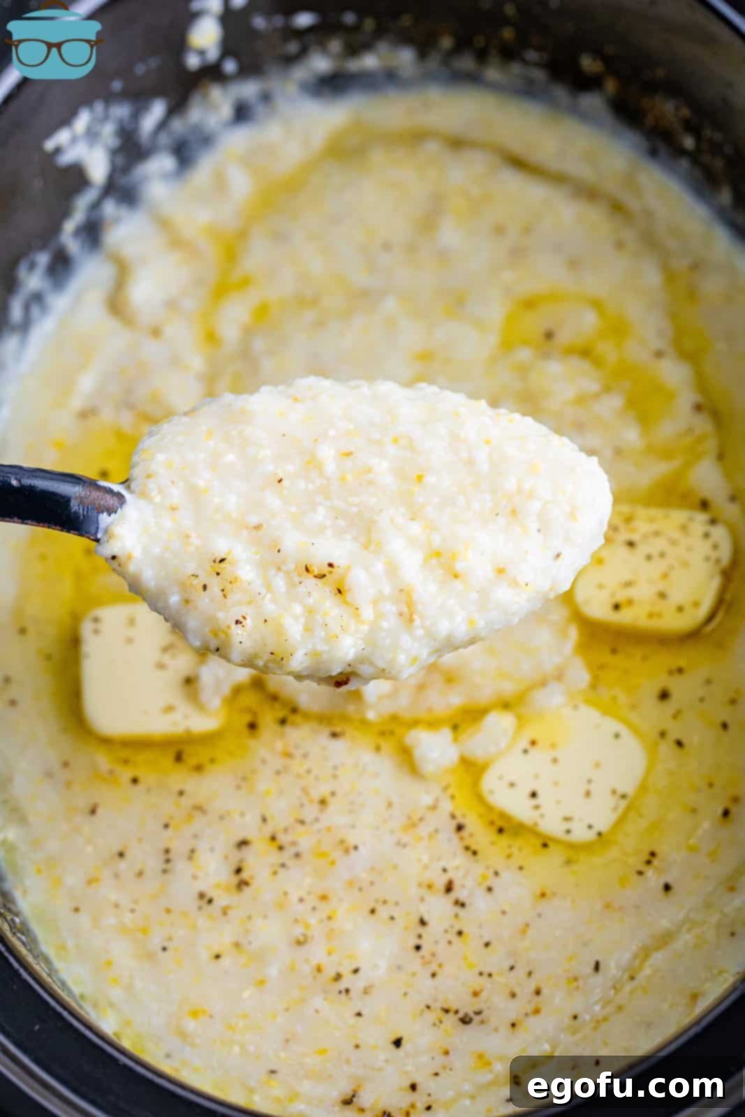 A spoon holding a bite of crockpot grits, showcasing its creamy texture.