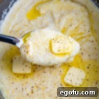 A spoon holding a bite of buttery southern grits, ready to be eaten.