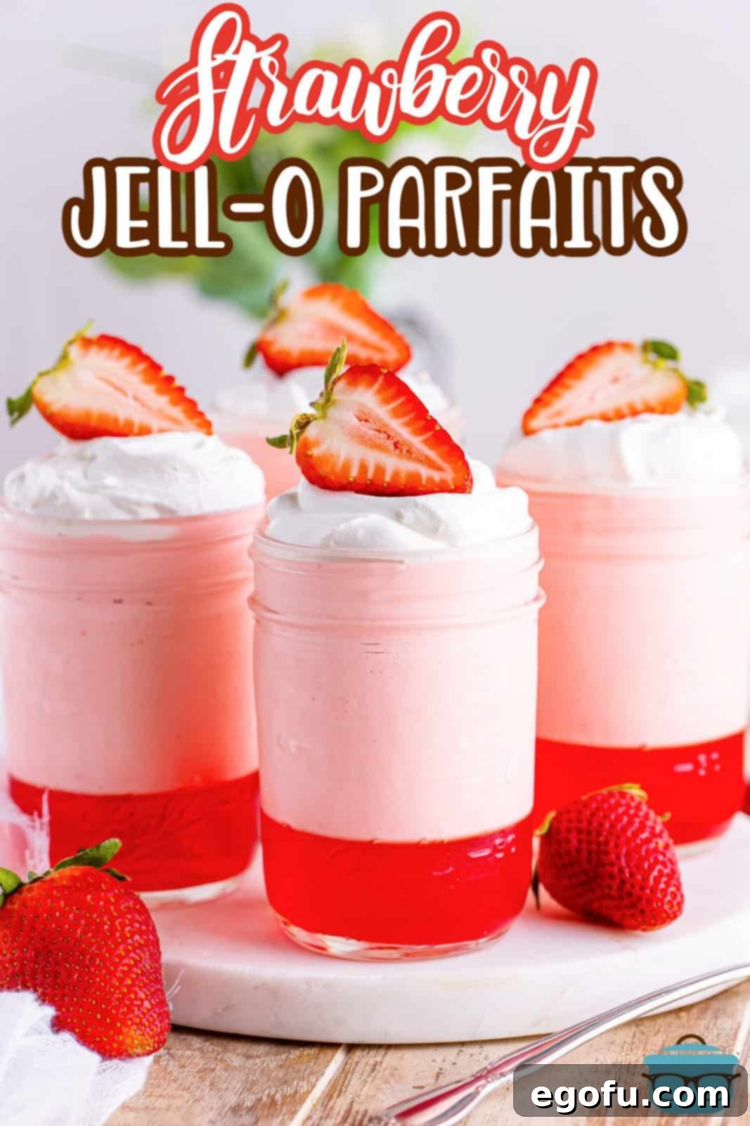 A few strawberry Jell-O parfaits sitting on a serving tray.