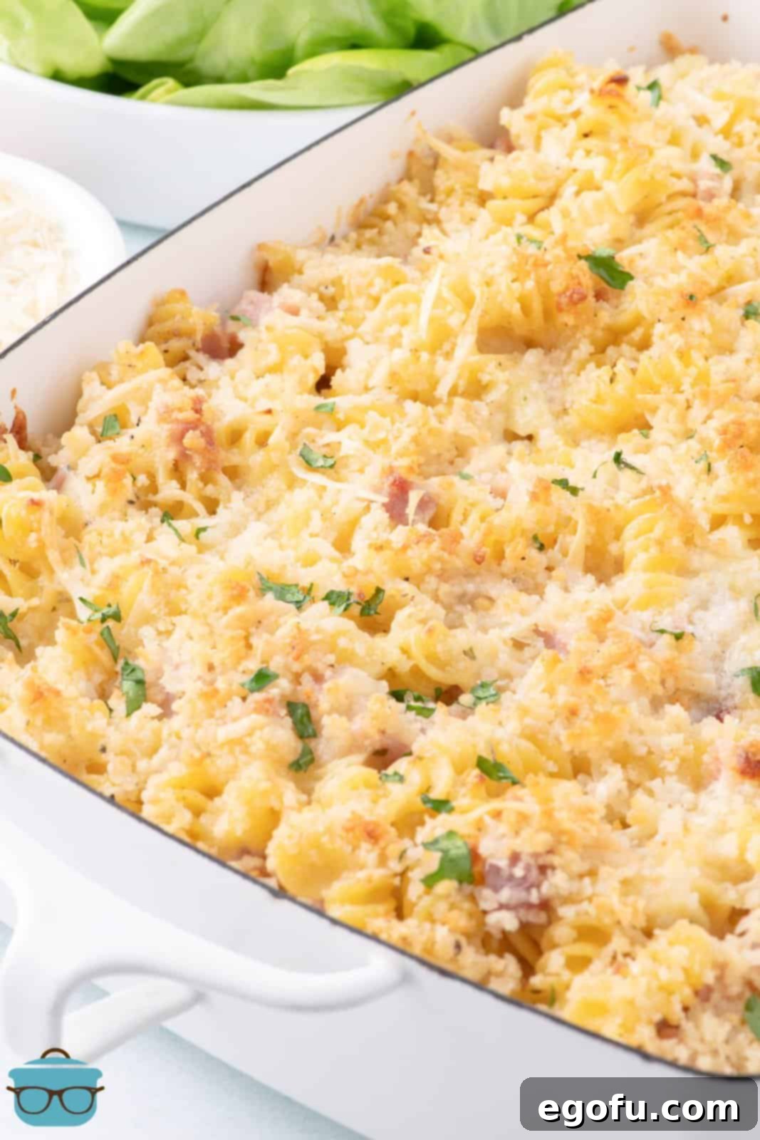 A baking dish full of homemade Ham and Cheese Casserole, garnished with fresh parsley.