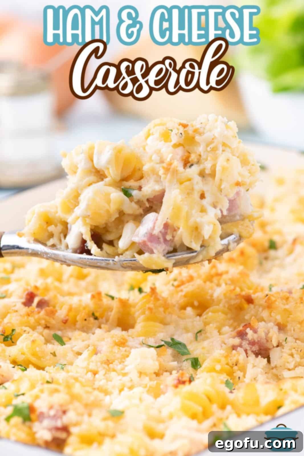 A serving spoon holding some Ham and Cheese Casserole over the dish, ready to be served.