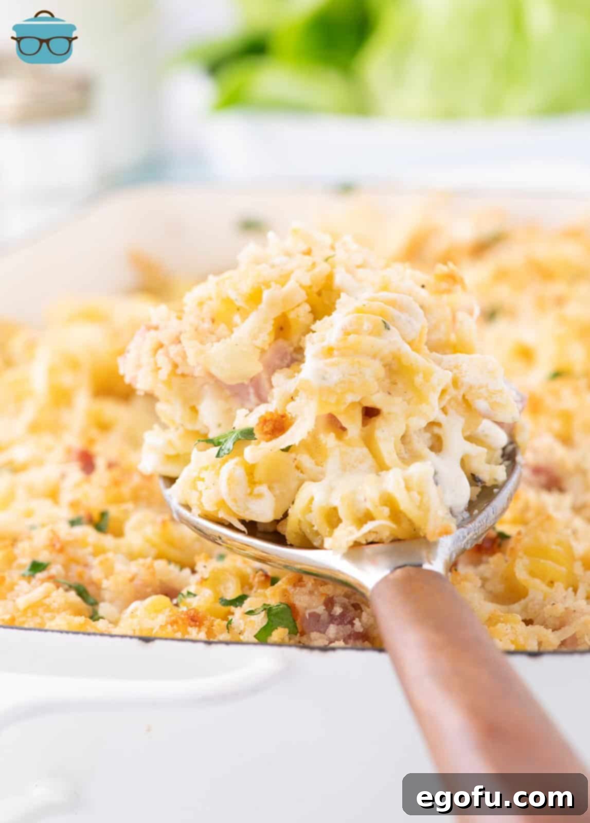 A serving utensil holding a spoonful of Ham and Cheese Casserole, showcasing its creamy texture.