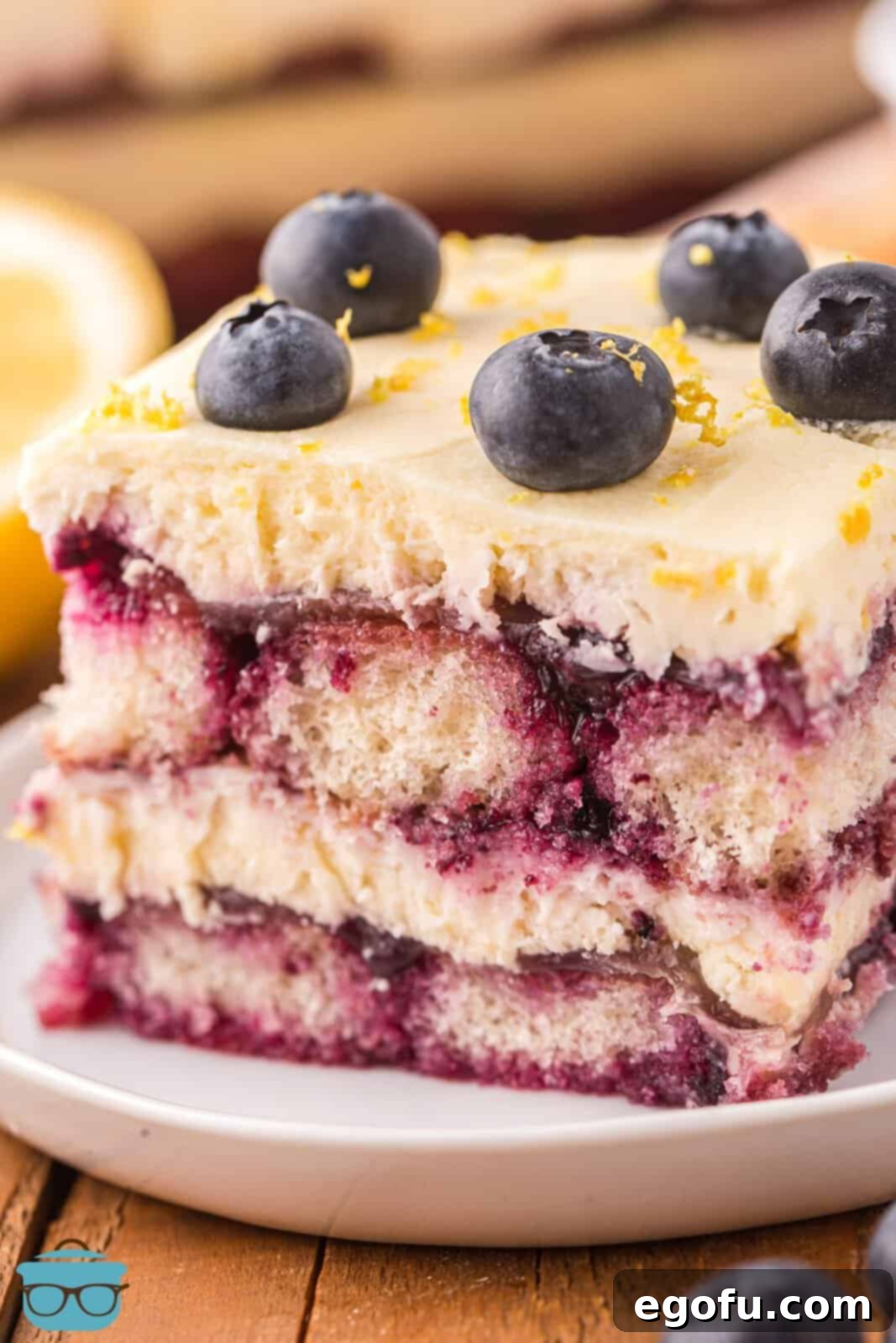 A slice of lemon blueberry tiramisu on a white plate, showcasing its beautiful layers of cream, fruit, and ladyfingers.