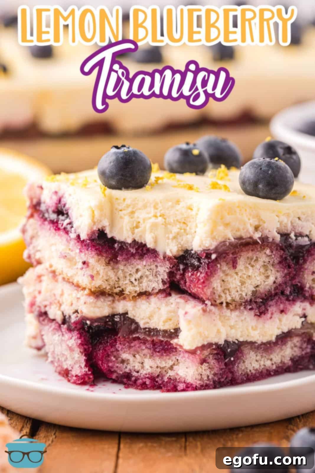 A piece of lemon blueberry tiramisu with a bite taken out, showing the creamy filling, soaked ladyfingers, and fruit layers.