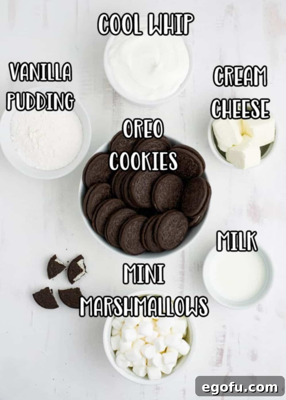 Individual ingredients for Oreo Fluff: instant vanilla pudding mix, whipped topping, softened cream cheese, a package of Oreos, cold milk, and a bag of mini marshmallows.