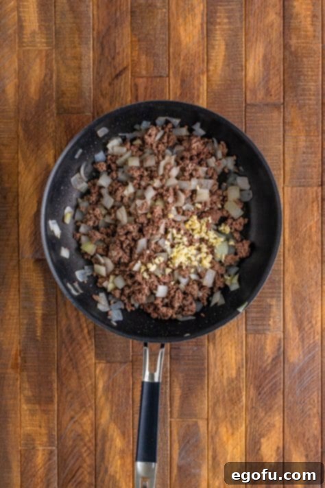 A skillet with ground beef, onion, and garlic.
