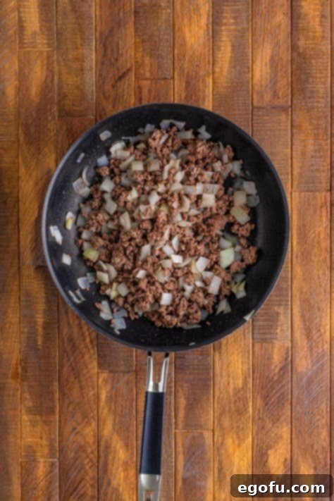 A skillet with ground beef and onion.