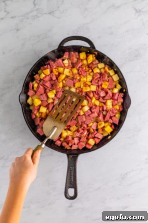 Homemade Corned Beef Hash 11 A spatula pressing down on the beef and potatoes.