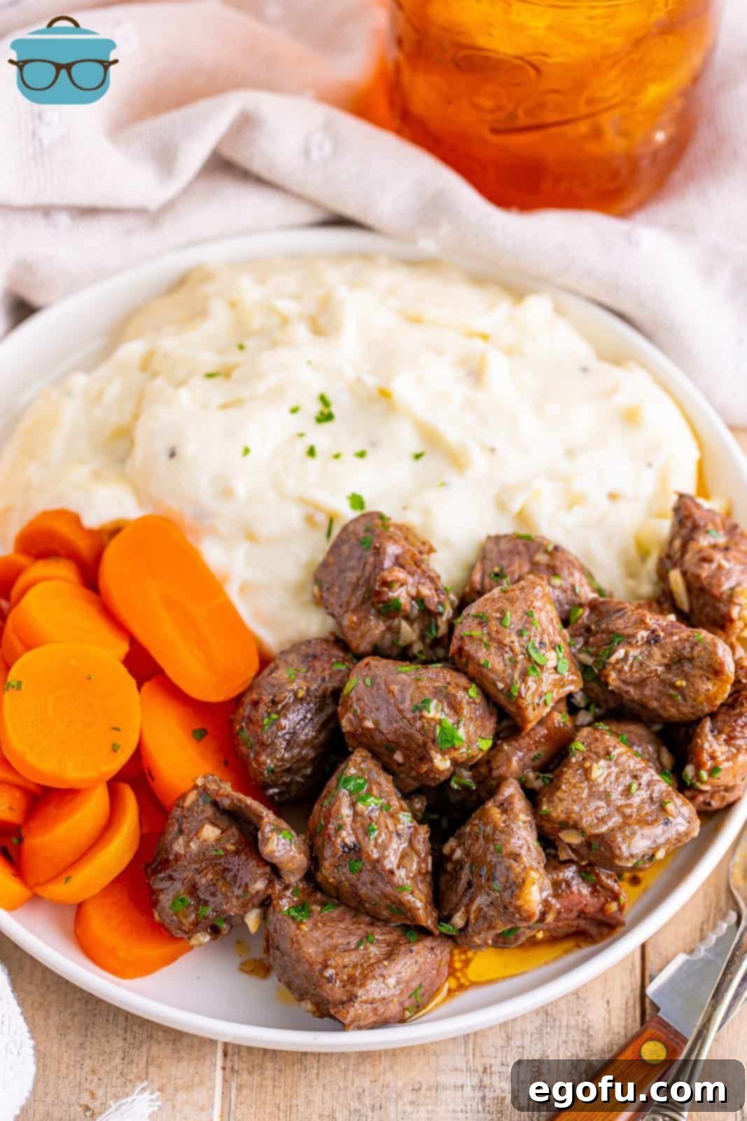 A plate with mashed potatoes, Air Fryer Garlic Butter Steak Bites and carrot pieces.