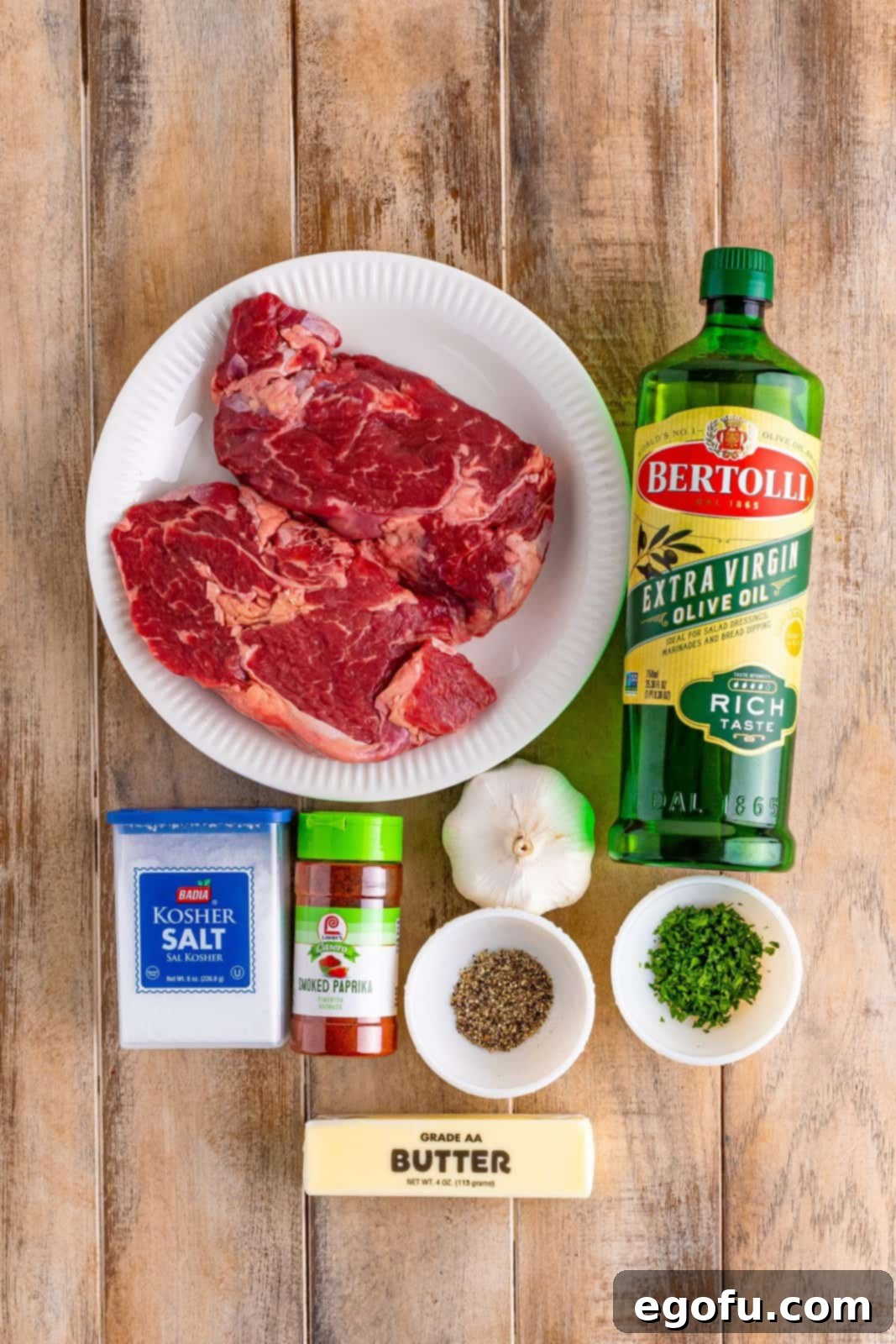 Boneless ribeye steaks, olive oil, kosher salt, fresh cracked black pepper, smoked paprika, salted butter, cloves garlic, and fresh chopped parsley.