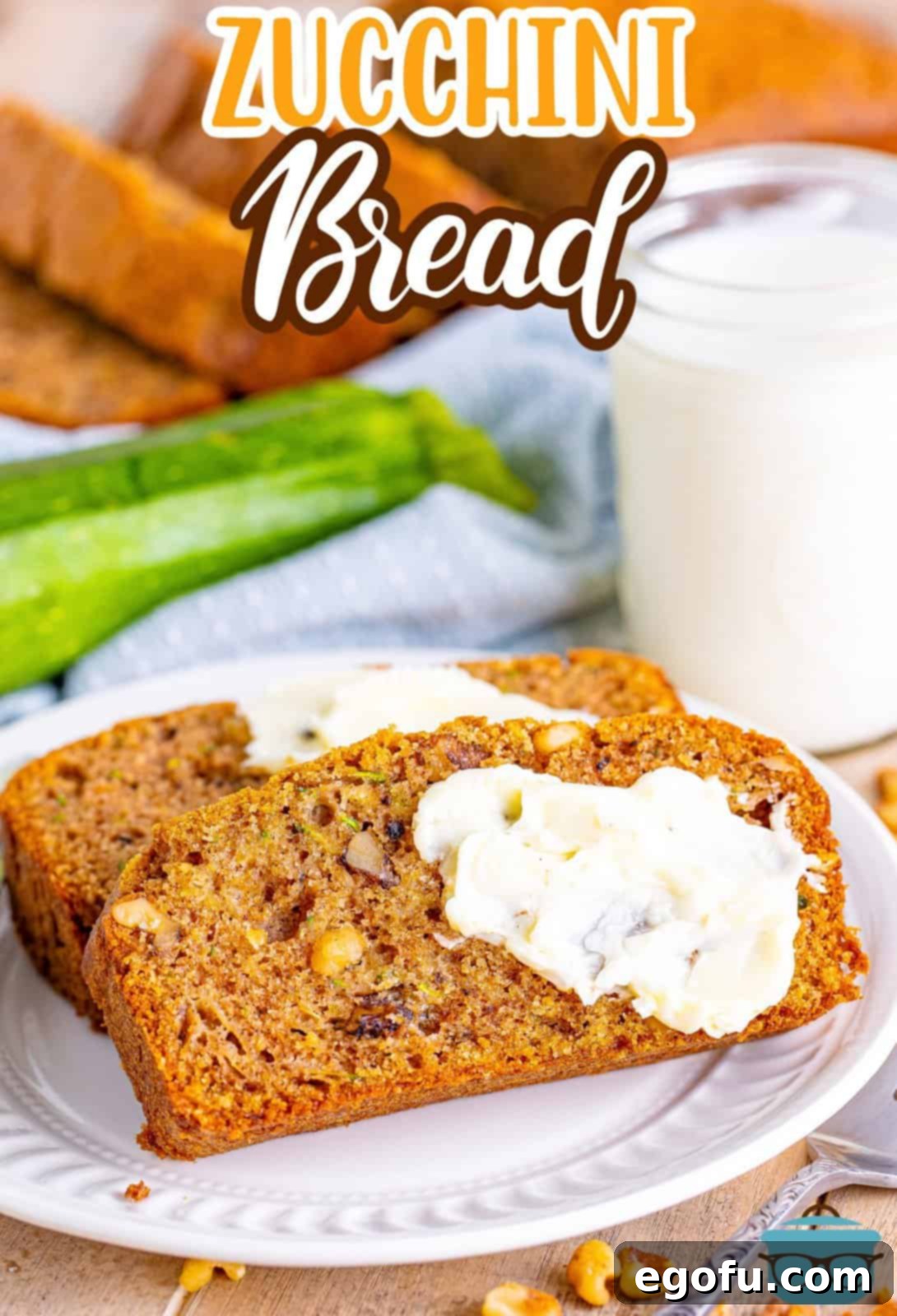 Two slices of moist zucchini bread with a creamy white glaze on top, placed on a white plate next to a fork.