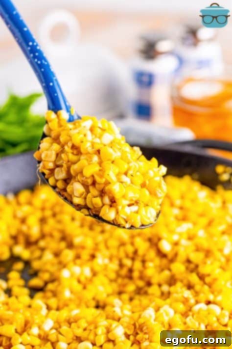 A serving spoon with a pile of Southern Fried Corn above the rest in a skillet.