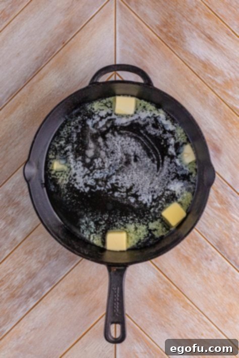 Butter and bacon grease melting in a cast iron skillet.