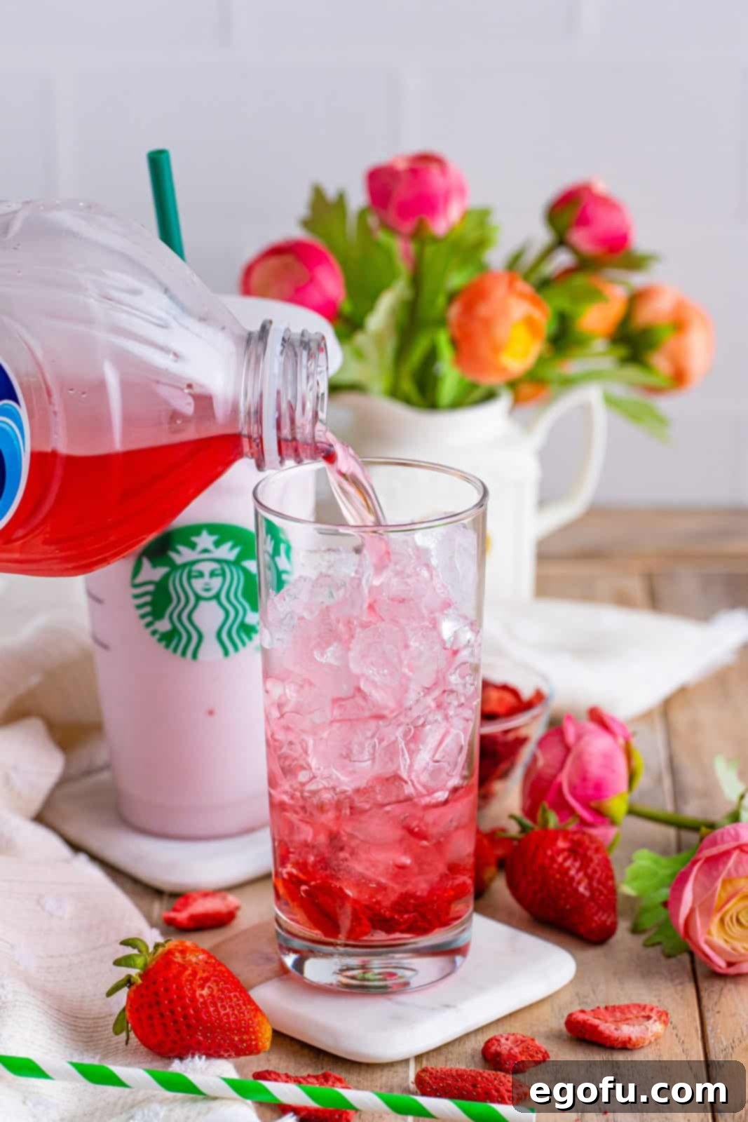 Starbucks' Iconic Pink Drink 5 Freeze dried strawberries and ice with white cran strawberry juice being poured in the glass.