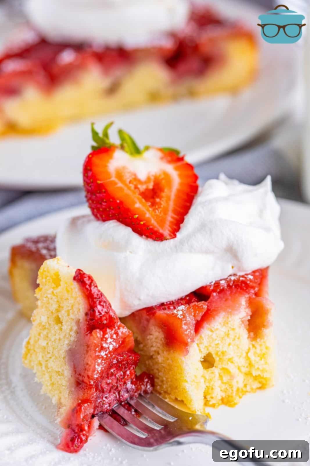 A delectable slice of Strawberry Upside Down Cake resting on a plate with a fork, ready to be enjoyed.