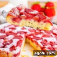 A serving utensil holding a slice of strawberry upside down cake.