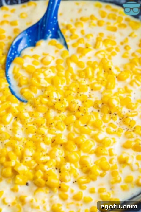 A blue spoon holding some creamed corn.