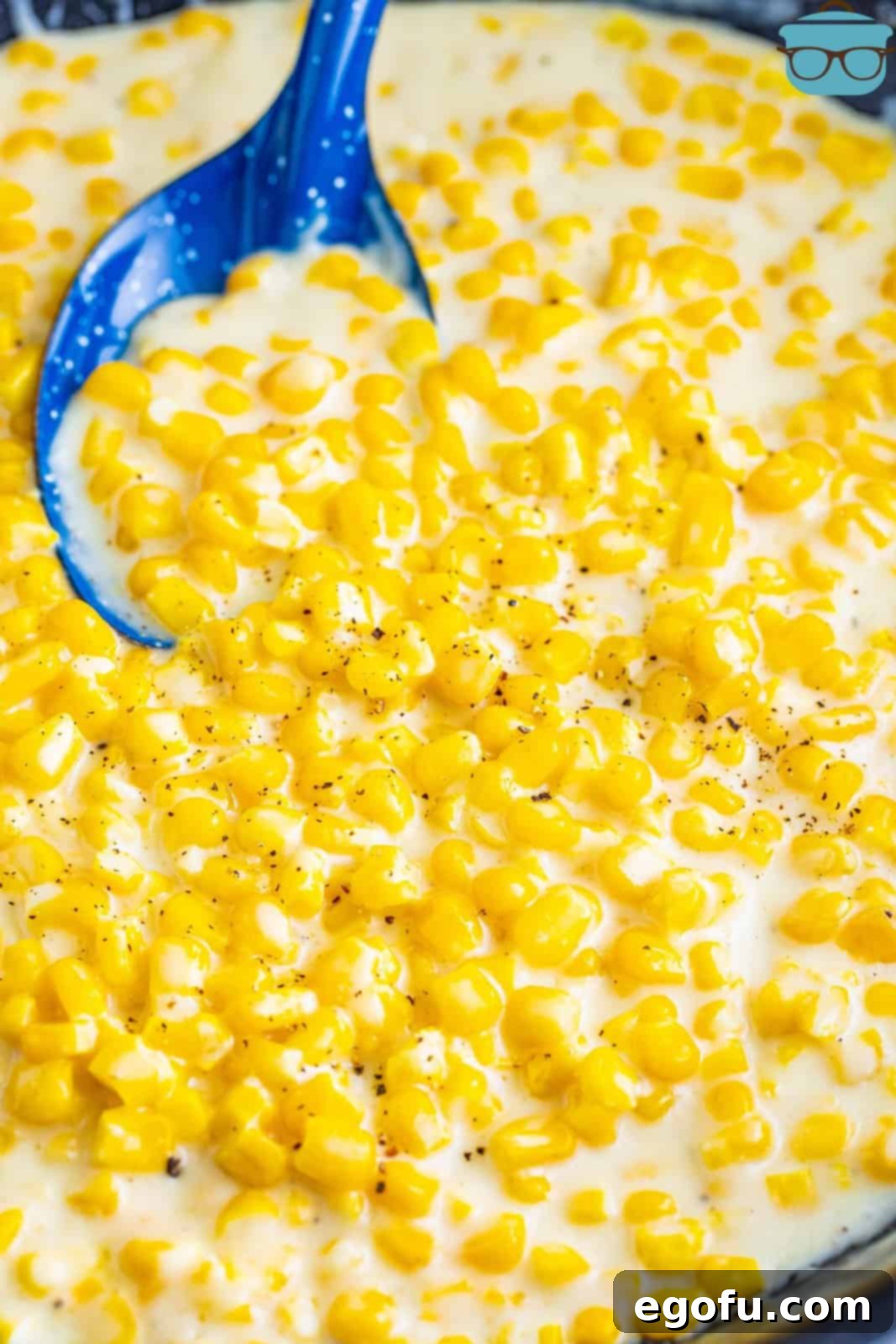A blue spoon holding some creamed corn.