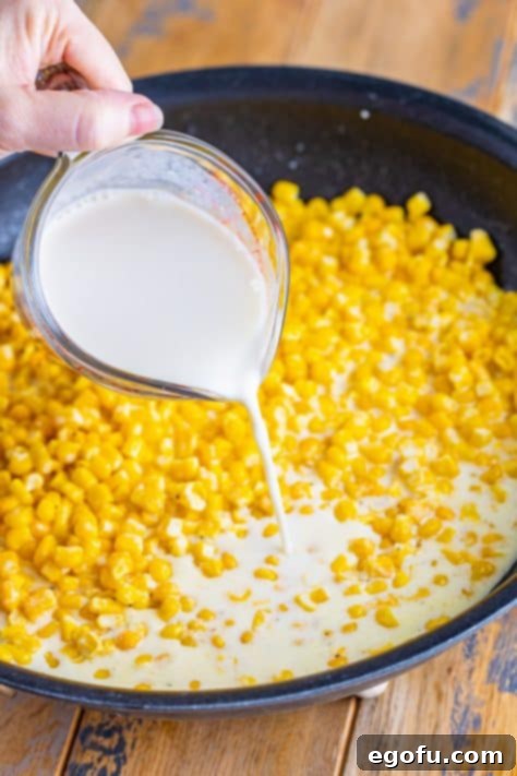 Milk being added to a skillet with corn.