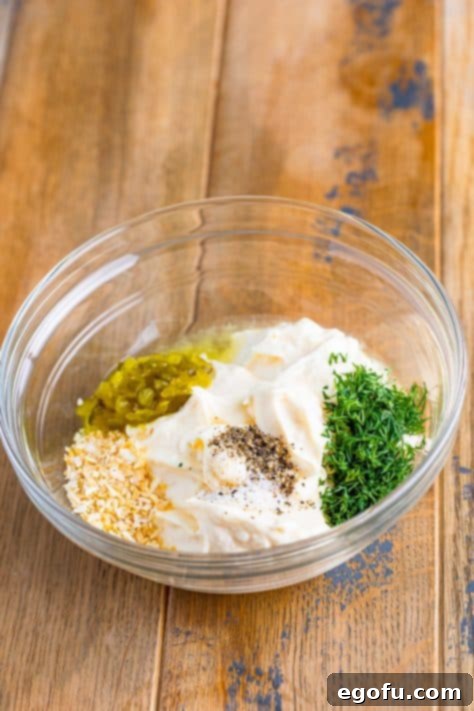 Tangy Homemade Tartar Sauce 9 A mixing bowl with mayo, minced garlic, dill, sweet pickle relish, salt and pepper.