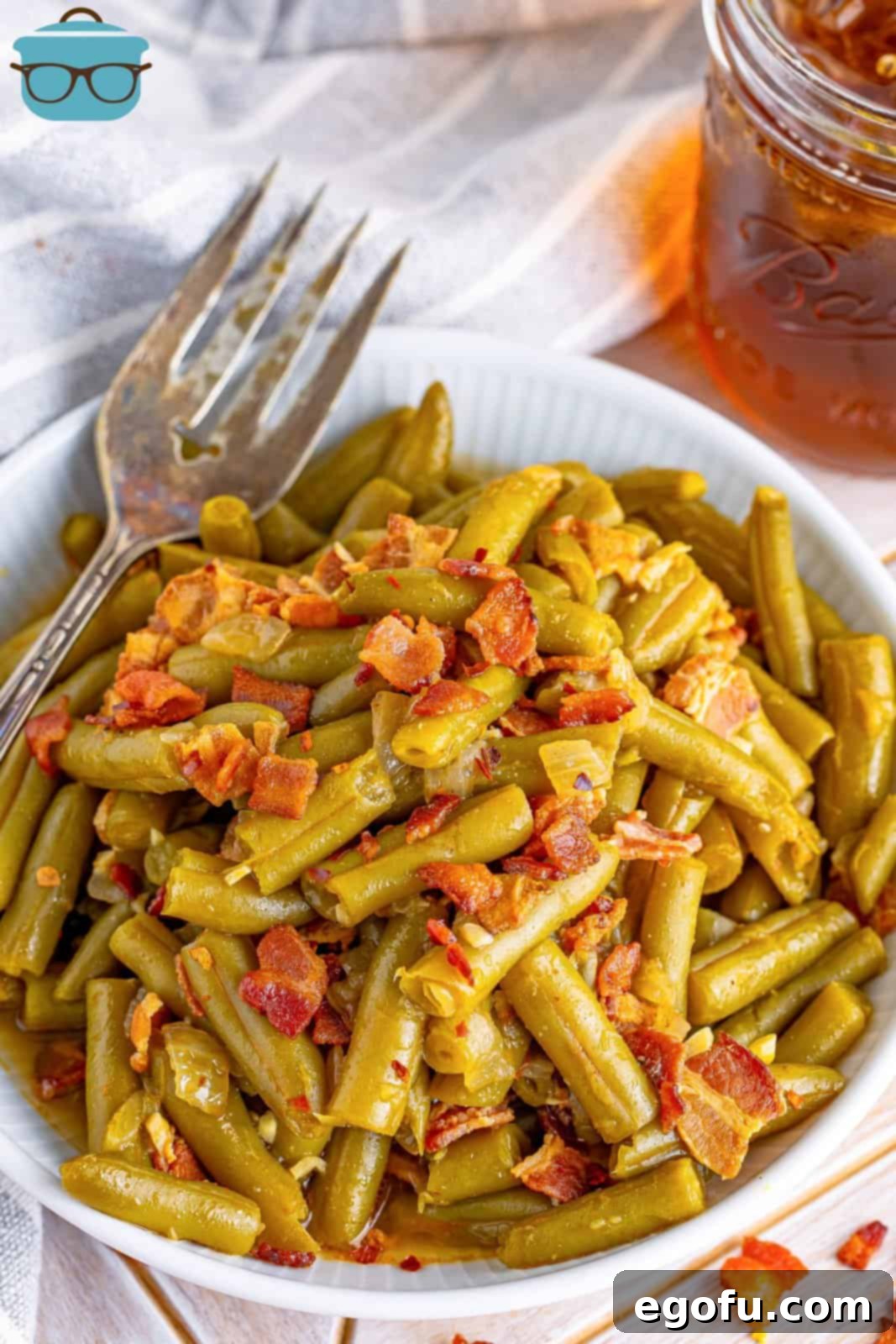 A close-up of slow cooker green beans with crispy bacon, served on a white plate, ready to be enjoyed as a comforting side.
