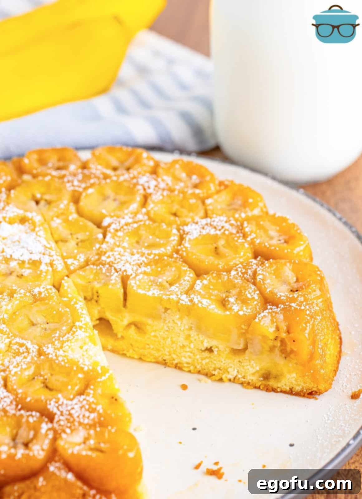 A slice of banana upside down cake removed from a larger cake on a serving plate, showing the caramelized banana topping.