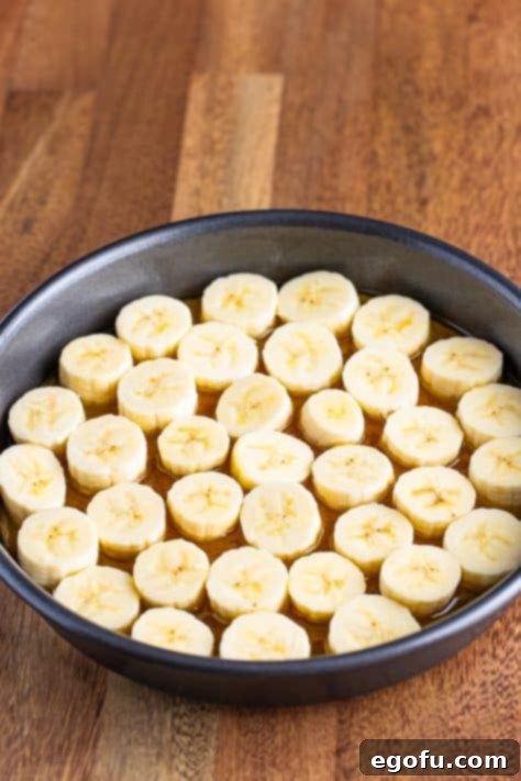 Sliced banana on top of the brown sugar butter mixture in a pan.