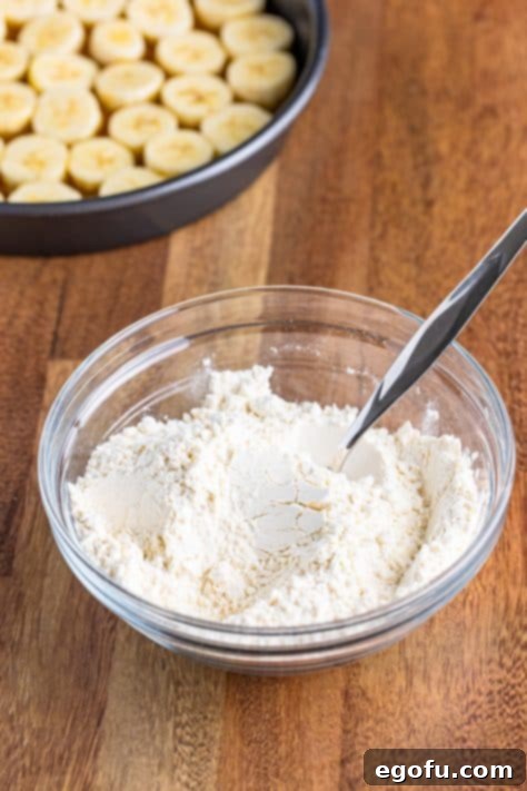 A bowl containing flour, baking powder, and salt, ready to be whisked together for the cake batter.