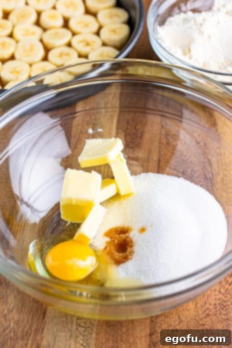 A mixing bowl with unsalted butter, granulated sugar, egg and vanilla extract being beaten until combined.