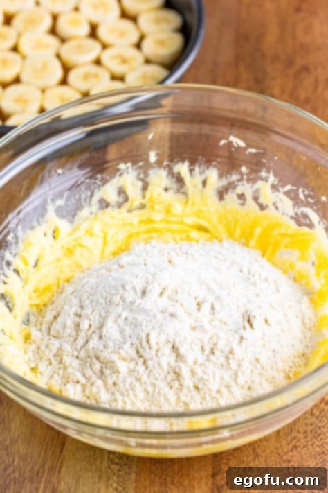 The dry flour mixture being added and mixed into the wet butter and sugar mixture, forming a crumbly batter.
