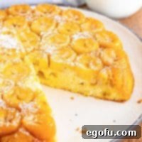 A beautifully baked banana upside down cake with a piece removed, showcasing its moist texture and caramelized banana topping.