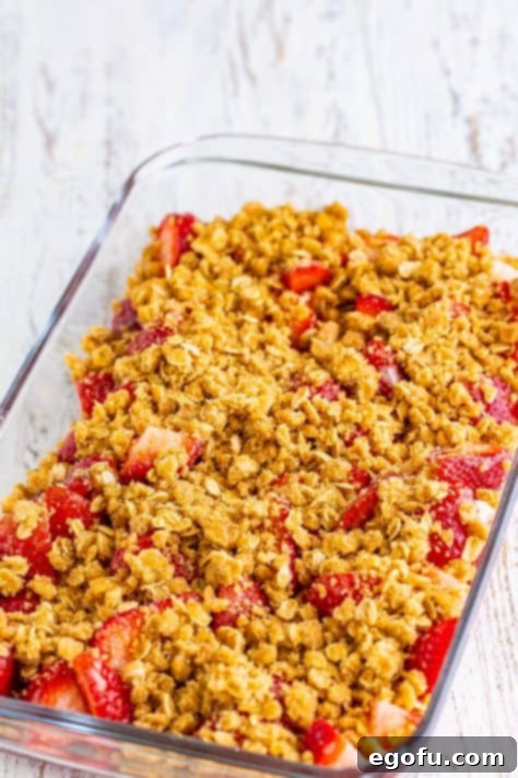 Sweet Strawberry Crumble 13 Crumble topping on top of the strawberries in a baking dish.