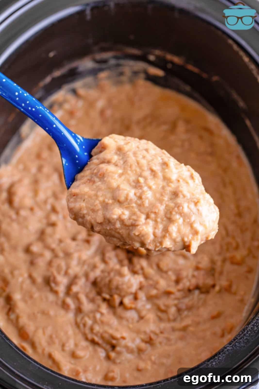 A serving spoon of refried beans above the Slow Cooker.