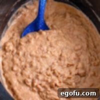 Closely looking at a slow cooker of refried beans.