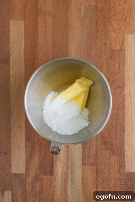 Softened butter and powdered sugar being creamed together in a mixing bowl.