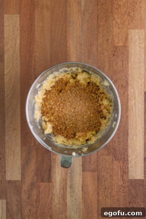 Crushed pecans resting on top of the mixed cookie dough, ready to be stirred in.