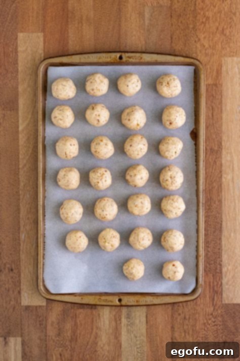 Rolled Pecan Sandies cookie dough balls on a parchment-lined baking sheet.