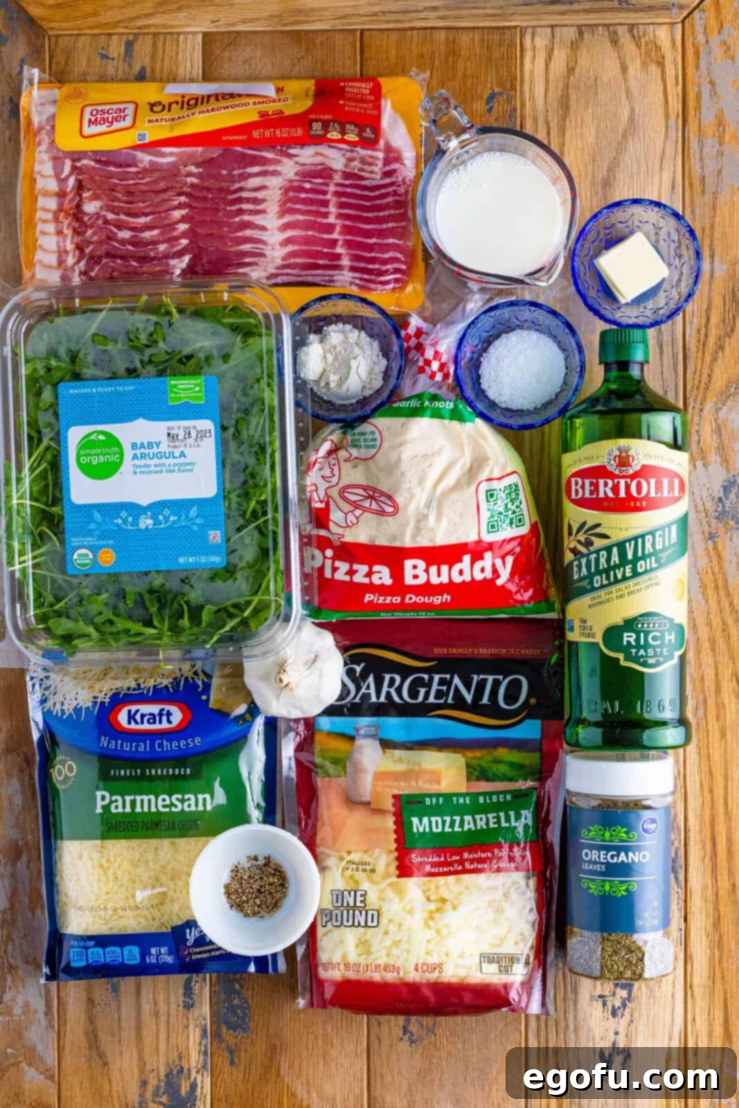 Arugula, bacon, olive oil, shredded parmesan and mozzarella cheese, salt, pepper, flour, pizza dough, butter, garlic, milk, and dried oregano.