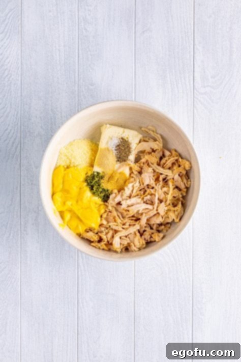 Savory Chicken Pockets 10 A mixing bowl with shredded chicken, cream cheese, can of chicken soup, grated Parmesan cheese, parsley, black pepper, kosher salt, garlic powder, and onion powder.