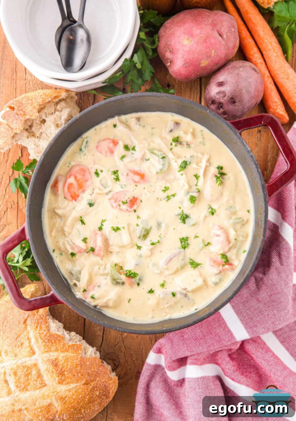 Looking down on a pot of creamy chicken stew and some ingredients surrounding it.